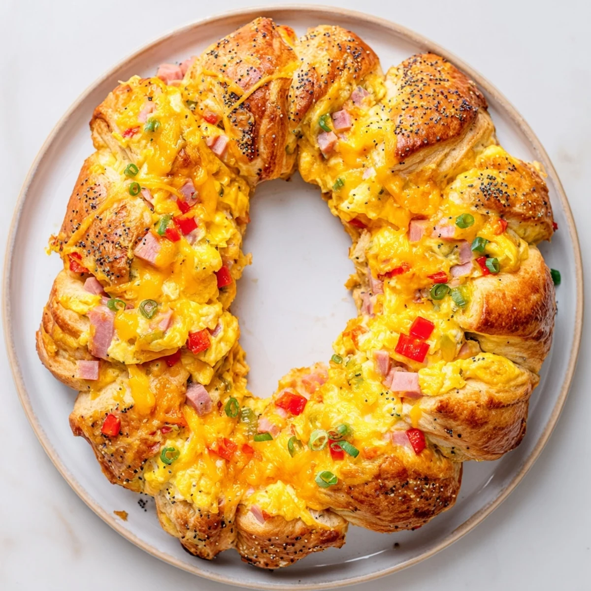 Fluffy baked wreath-shaped egg and ham bake, a savory brunch main dish, featuring fresh ingredients.