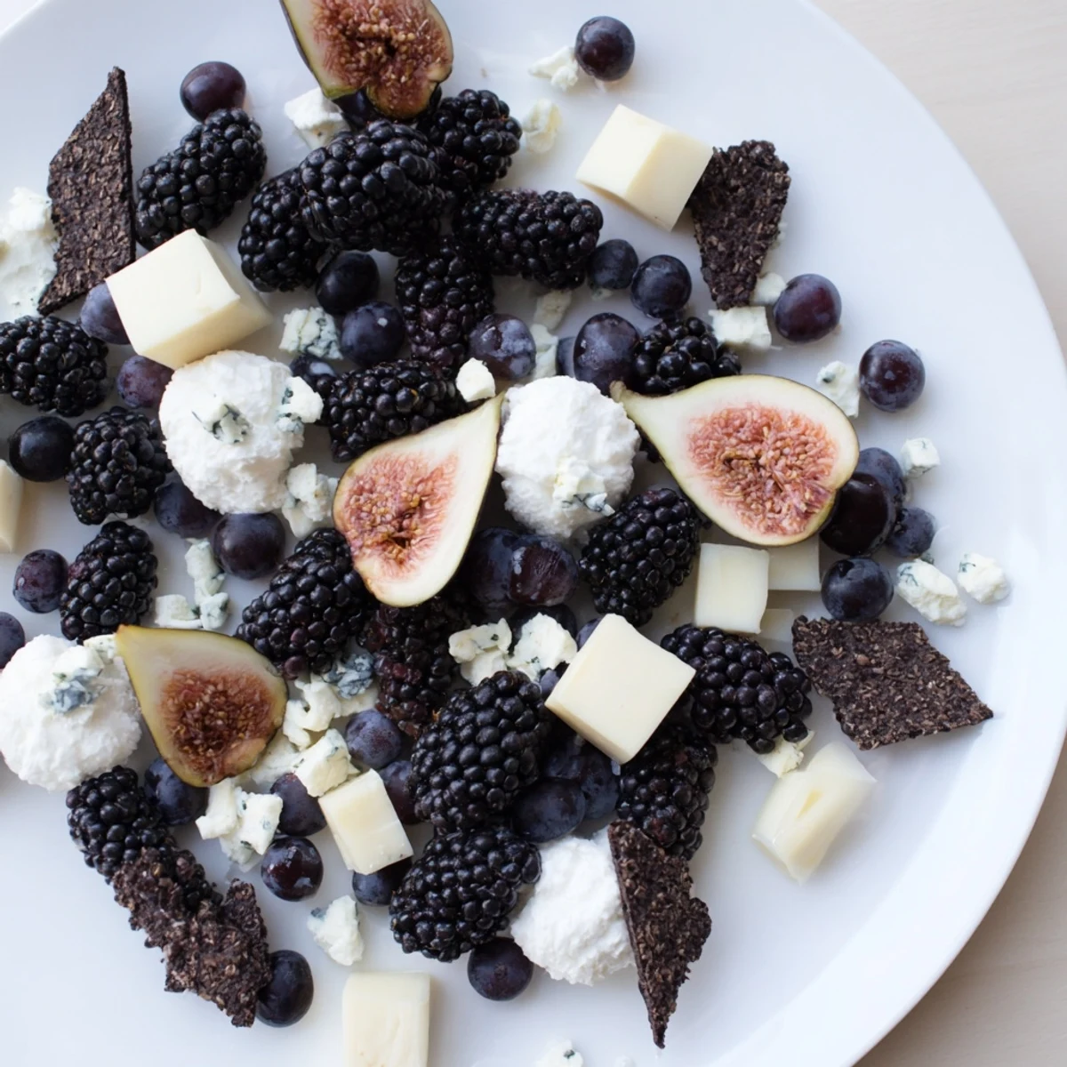 A visually appealing Deep Indigo Midnight Sky cheese board with blackberries, figs, and creamy cheeses.