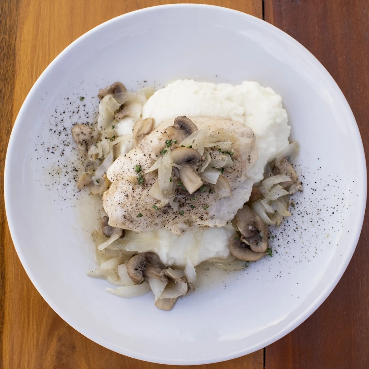 The Ghostly Gala features creamy cauliflower puree and tender chicken, elegantly plated with pepper shadows.