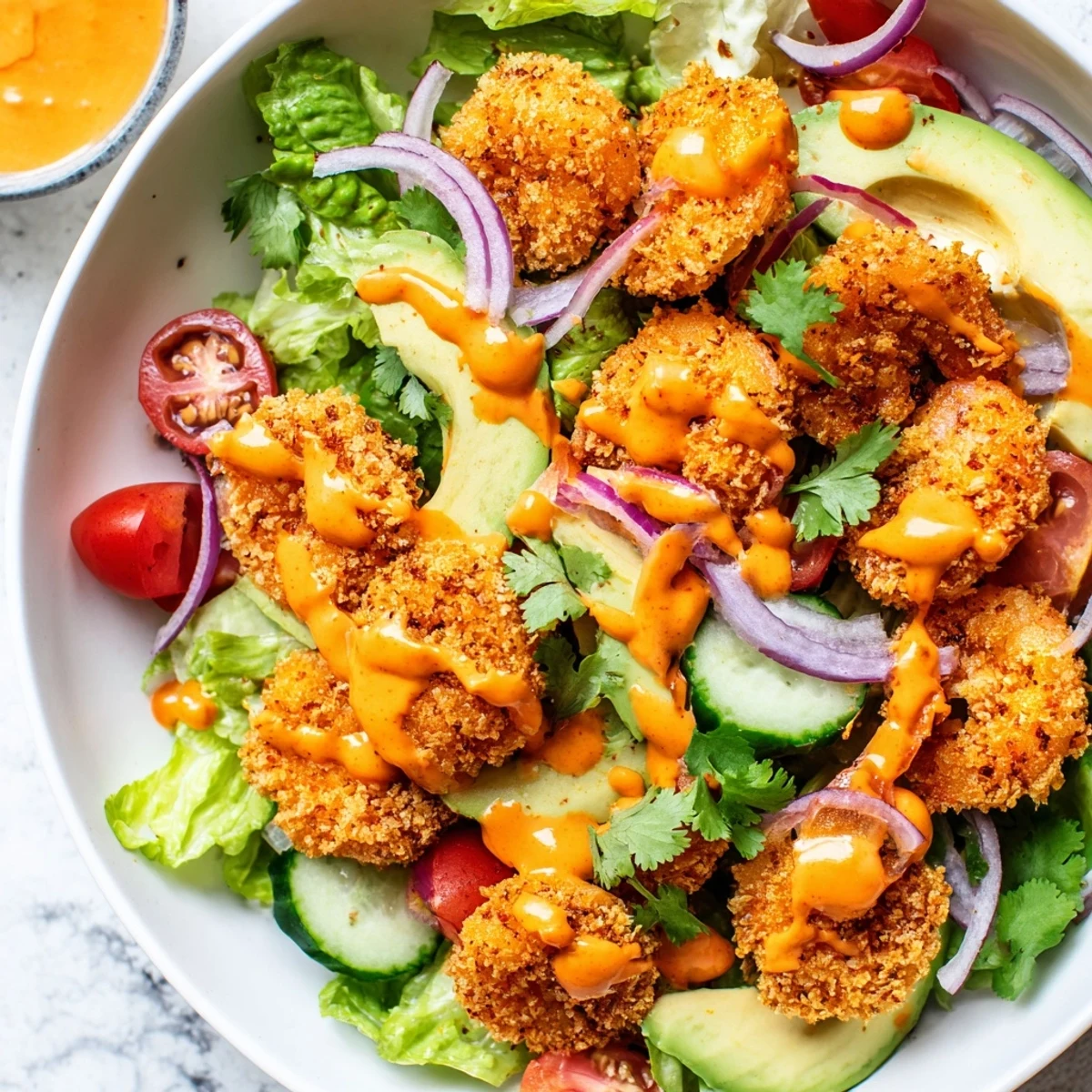 Golden, crunchy Spicy Crispy Shrimp Salad paired with creamy avocado and fresh vegetables in a bowl.