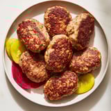 Juicy, savory Danish frikadeller meatballs nestled next to tangy pickles, a classic Danish dinner.