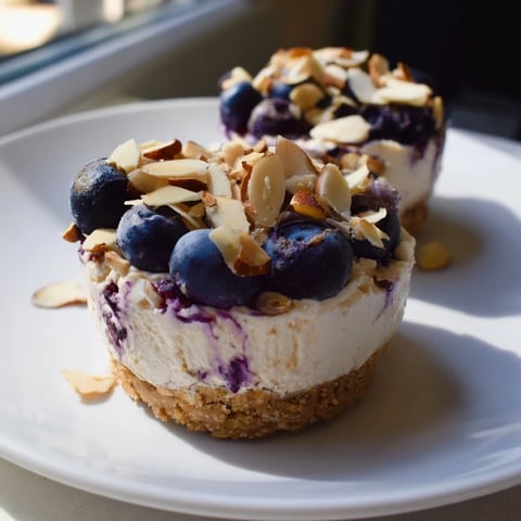 Protein cheesecake cups, ready to eat, topped with fresh berries and nuts, a delightful treat.