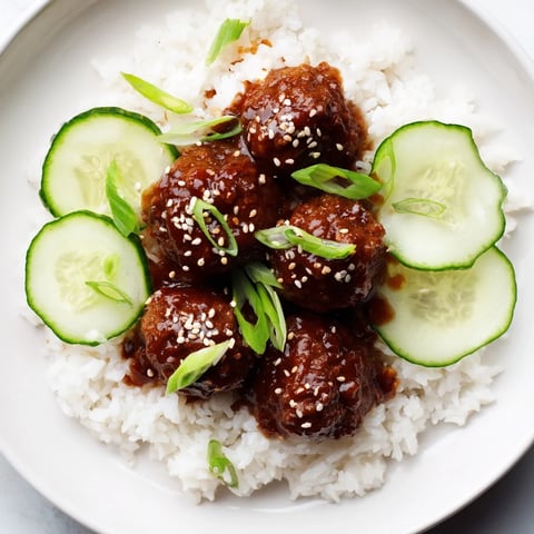 Steaming, delicious teriyaki meatball bowls featuring tender meatballs coated in a glossy, savory glaze over rice.