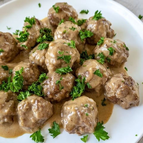 Golden brown Swedish Meatballs swimming in a rich, creamy sauce, ready to serve with mashed potatoes.