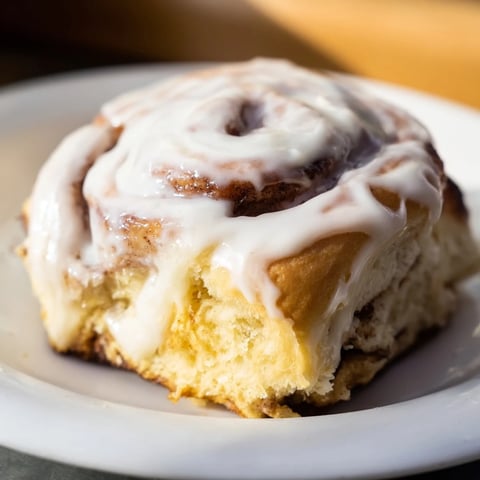 Freshly baked Pillow Soft Cinnamon Rolls, golden brown and dripping with cream cheese glaze, ready to serve warm for breakfast.