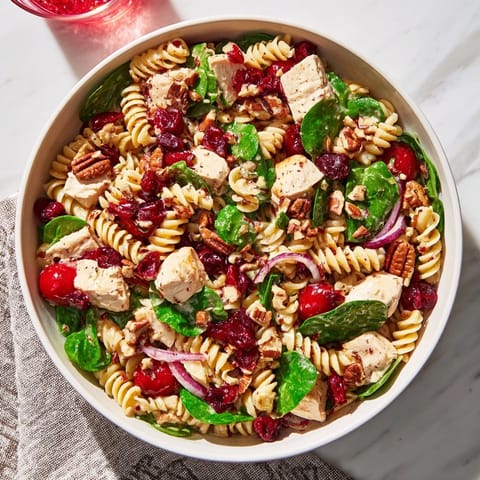 Refreshing Pasta Salad with Cranberry Vinaigrette features rotini, chicken, and a vibrant cranberry dressing.