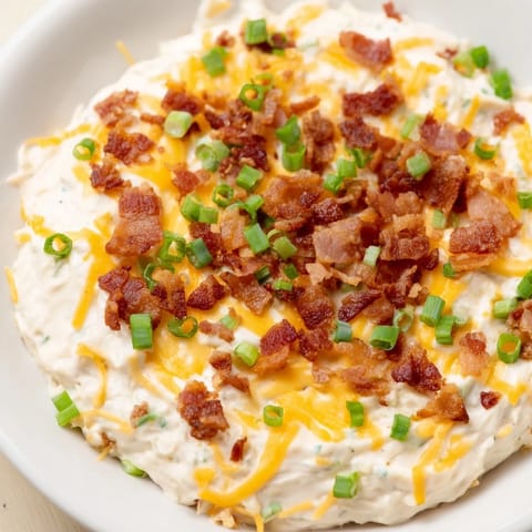 Warm, gooey Cheesy Bacon Ranch Dip fresh from the oven, served with a colorful assortment of chips.