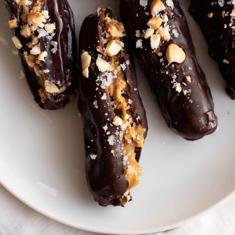 A close-up of decadent Chocolate Date Snickers, with rich dark chocolate, appealing peanut butter.