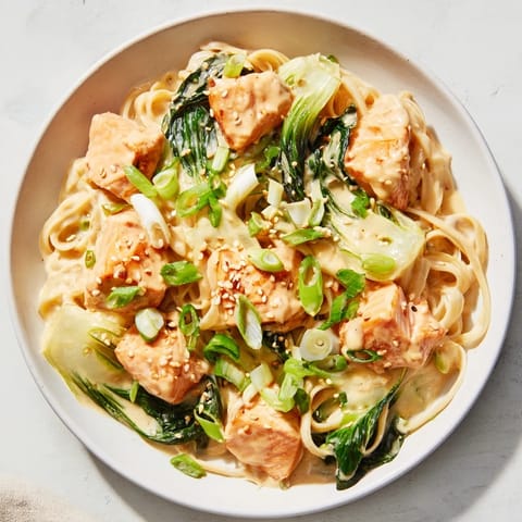 Golden-brown Miso Butter Salmon Pasta, the salmon flaked over the linguine, ready to serve with scallions.