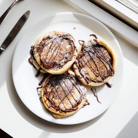 Golden-brown Nutella stuffed pancakes topped with powdered sugar, sliced bananas, and maple syrup on a rustic plate.  