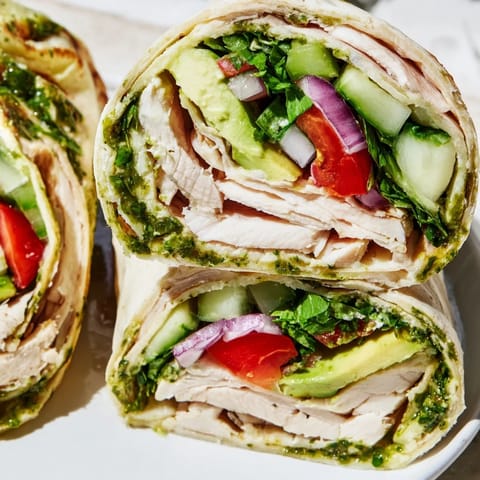 Juicy chimichurri-marinated chicken, crisp greens, and zesty sauce rolled in a soft tortilla for a fresh meal.