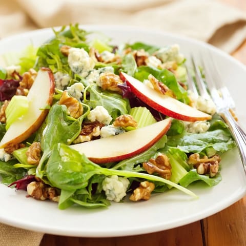 This Apple and Walnut Salad showcases thin apple slices and chopped walnuts tossed with greens, crumbled feta, and a light honey-mustard dressing.  