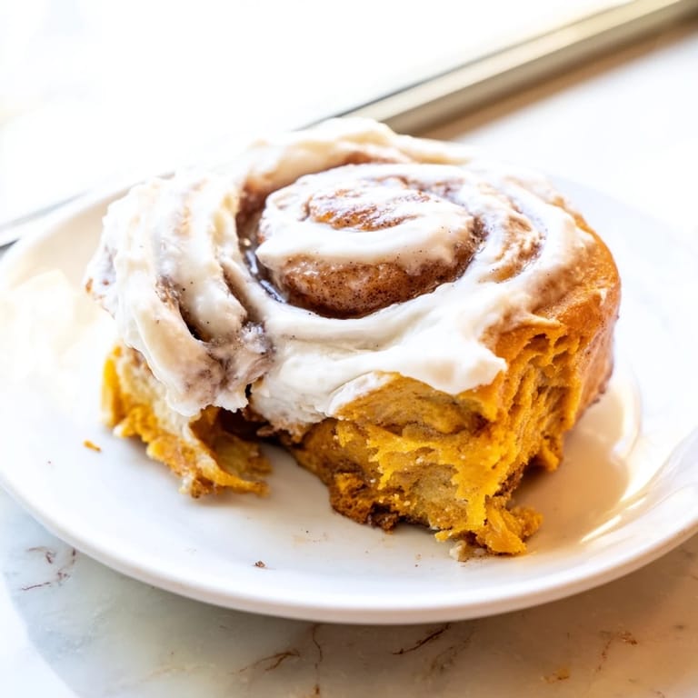 Homemade Pumpkin Cinnamon Rolls on a rustic wooden table, ready to serve for a cozy autumn breakfast.