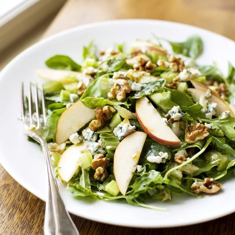 Colorful Apple and Walnut Salad served in a white bowl with fresh greens, apple wedges, walnuts, and a drizzle of tangy vinaigrette.