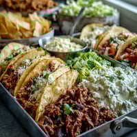 Festive Cinco de Mayo taco bar spread with grilled chicken, beef, and toppings for DIY taco fun.